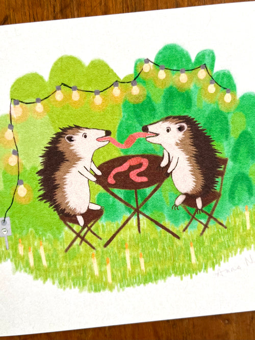 Fine art print van een tekening van twee egels die aan het picknicken zijn en samen een worm eten. Getekend door Anne Neuteboom cabaretier Anne Neut Boetiek.