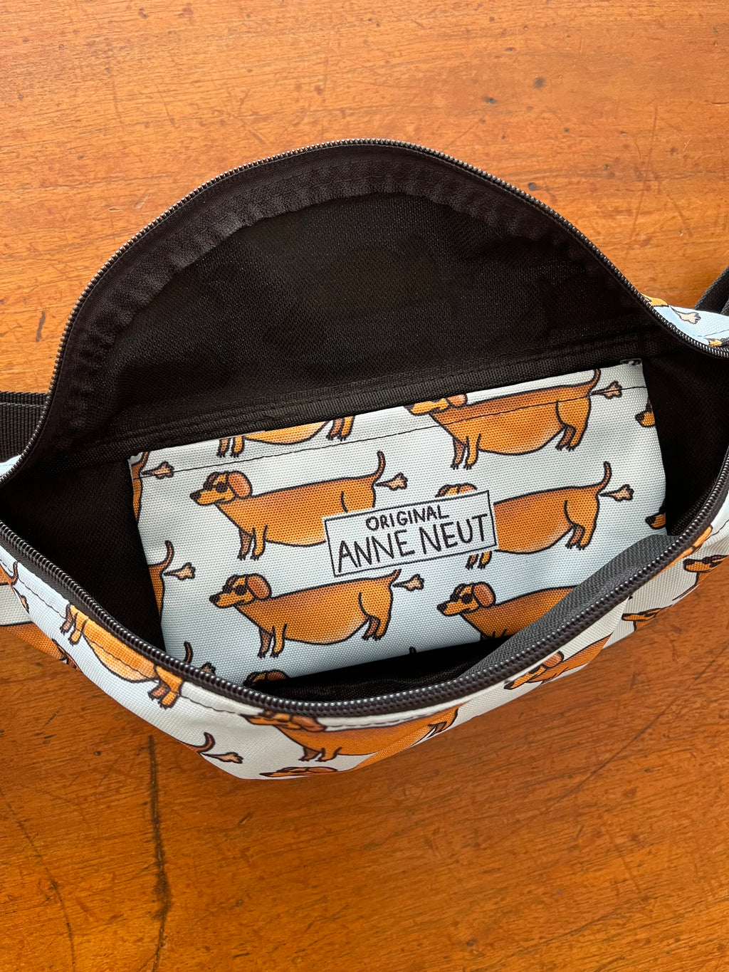 fanny pack met tekening van teckels die scheetjes laten door Anne Neuteboom cabaretier Anne Neut Boetiek