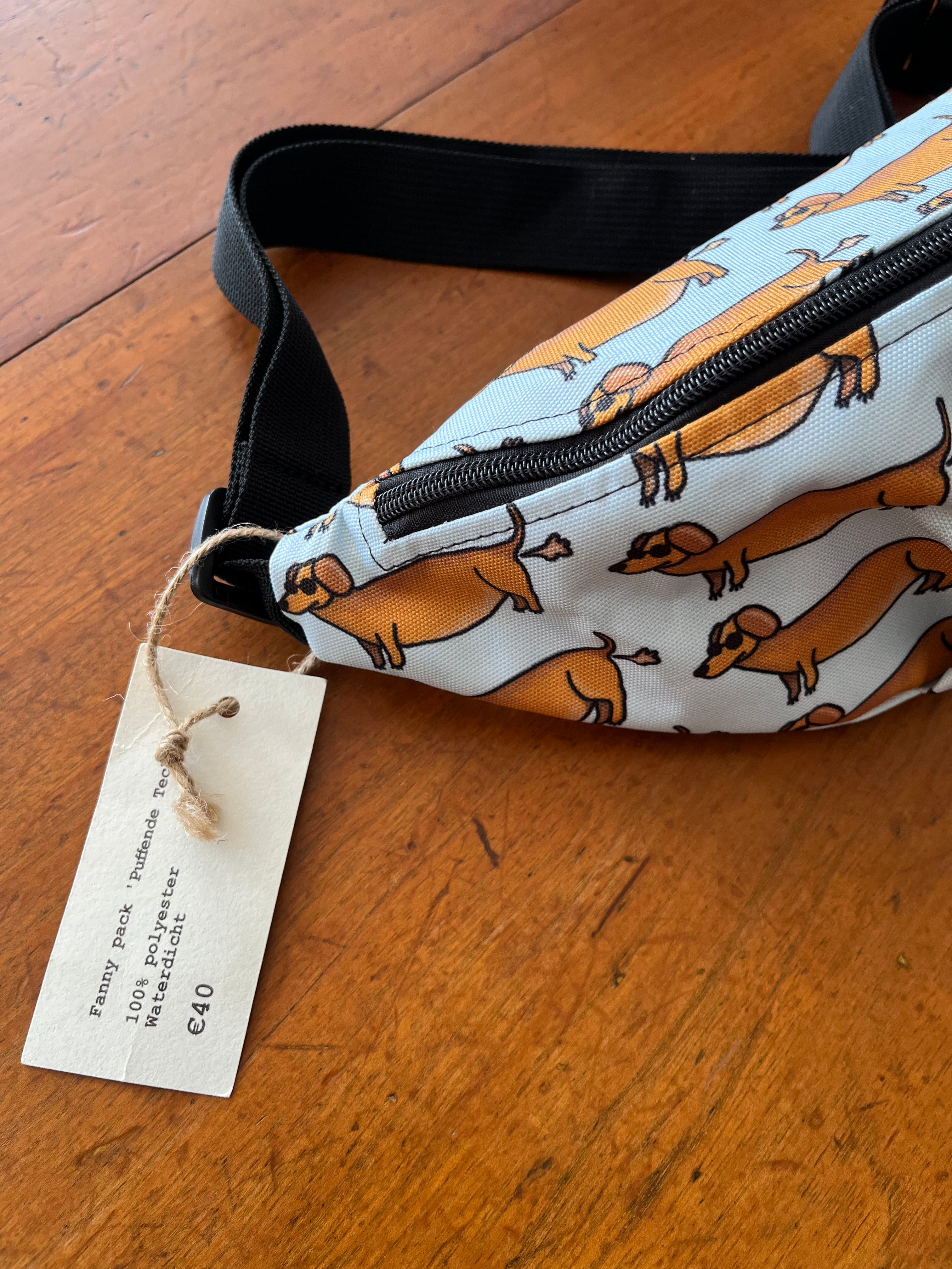 fanny pack met tekening van teckels die scheetjes laten door Anne Neuteboom cabaretier Anne Neut Boetiek